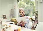 Smiling mature woman using digital tablet at breakfast table