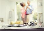 Mature couple dancing in living room behind record player