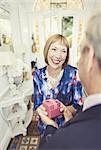 Smiling mature woman receiving gift from husband