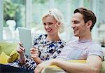 Couple using digital tablet on living room sofa