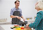 Smiling couple cutting and cooking vegetables in kitchen