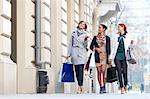 Women with shopping bags talking and walking on city sidewalk