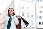 Smiling woman carrying shopping bags in city