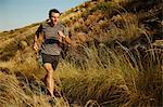 Man running on trail through tall grass