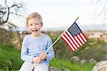 smiling boy holding american flag and celebrating 4th of july