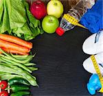 healthy lifestyle concept - training shoes, vegetables  and  water on black table with copy space