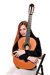 Young woman sitting poses in the studio hug a classical guitar. Isolation on white background. Smiling.