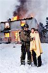 Fireman with rescued senior woman in front of burning house