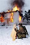 Fireman holding rescued girl, burning building in background