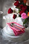 Roses in vase with stack of plates