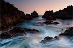 Scenic view of rocky coastline at dusk