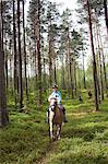 Girl horseback riding through forest