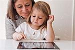 Grandmother with granddaughter using digital tablet