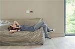 Woman lying on plastic covered sofa