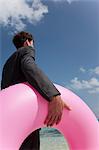 Businessman carrying inner tube on beach