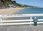 Toddler looking over railing on pier