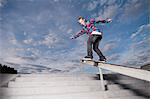 Skater sliding down rail on board