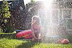 Young girl playing in garden sprinkler