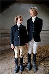 Boys wearing horse riding clothes in stable