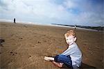 Boy sitting on beach smiling