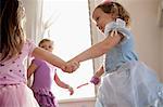 Three young girls in party dress holding hands and dancing