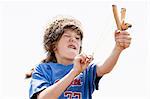 Boy wearing trapper's hat playing with sling shot