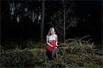 Young woman sitting in forest holding a digital tablet