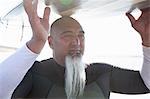 Close up of mature male surfer balancing surfboard on head