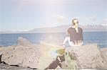 Rear view of teenage girl looking out at view of mountain range over water, Reykjavik, Iceland