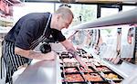 Butcher serving fresh food from refrigerator in butchers shop