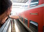 Italy, woman looking through train window at train station