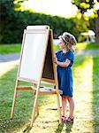 Girl painting at easel on lawn