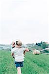 Father carrying children through field