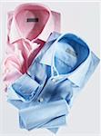 Two shirts, pink and blue, on white background, studio shot