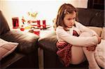 6 year old girl sitting on a sofa at Christmas looking sad, Germany