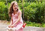 5 year old girl sitting on a swing in the garden, Germany