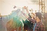 Enthusiastic young adults toasting cocktails at rooftop party