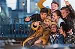 Enthusiastic young adult friends taking selfie at rooftop party