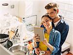 Affectionate young couple using digital tablet in apartment kitchen