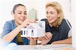 Young female architects assembling house model