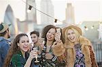Portrait enthusiastic young women drinking champagne at rooftop party