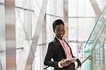 Portrait confident corporate businessman with digital tablet in modern office lobby