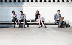 Corporate business people working on sunny bench outdoors