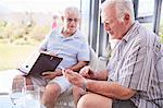 Senior men texting with cell phone on patio