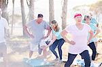 Yoga instructor guiding senior man in sunny park