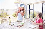 Mother hugging senior mother at patio lunch