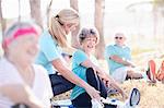 Yoga instructor guiding senior woman in sunny park