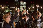 Young men toasting beer bottles at rooftop party