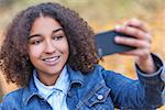 Beautiful happy mixed race African American young woman girl teenager female child smiling with perfect teeth taking selfie photograph in fall or autumn