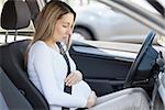 Young pregnant woman behind the steering wheel having contractions